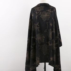 May include: Black fabric with a floral pattern in a light brown colour. The fabric is draped over a mannequin.