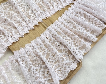 May include: White lace trim with a delicate floral pattern. The lace is gathered and ruffled, creating a soft and romantic look.