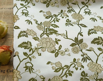 May include: White fabric with a repeating pattern of green leaves and beige flowers. The fabric has a subtle sheen and a slightly textured surface.