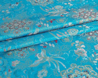 Könnte beinhalten: Blauer Stoff mit einem goldenen und silbernen Brokatmuster mit Blumen, Vögeln und geometrischen Mustern.