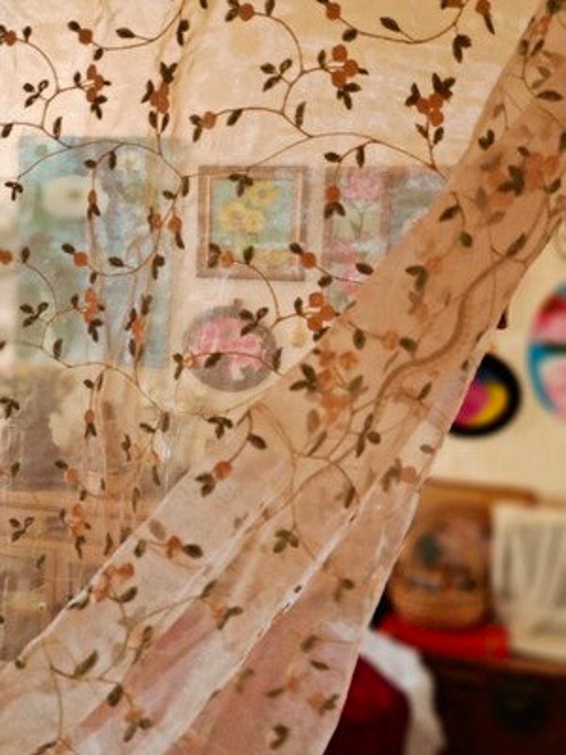 May include: A sheer curtain with a floral pattern in shades of brown and beige. The curtain is made of a delicate fabric and has a flowing, romantic look.