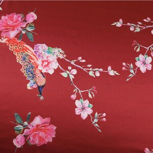 Peut inclure: Un tissu rouge avec un motif floral et paon. Le motif pr&eacute;sente un paon avec une queue color&eacute;e, des roses roses et des branches d&eacute;licates avec des fleurs roses et des feuilles vertes. Le fond est rouge fonc&eacute; uni.