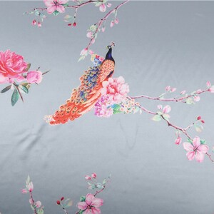 Peut inclure: Un tissu orn&eacute; d'un motif r&eacute;p&eacute;t&eacute; de paon, de fleurs et de branches. Le paon a une t&ecirc;te et un cou bleus, avec une queue color&eacute;e. Les fleurs sont roses et les branches ont des fleurs roses. Le fond est gris clair.