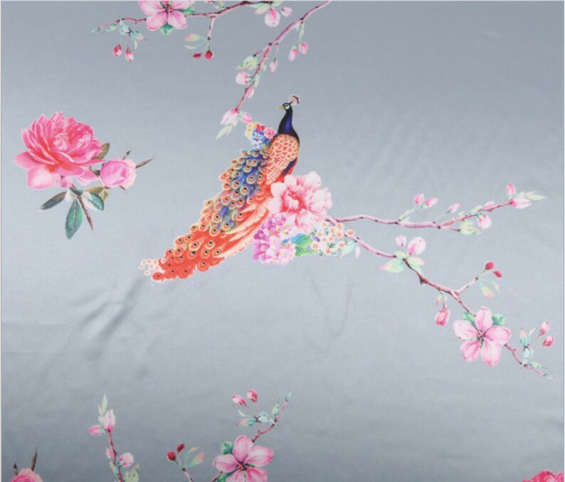 Peut inclure: Un tissu orn&eacute; d'un motif r&eacute;p&eacute;t&eacute; de paon, de fleurs et de branches. Le paon a une t&ecirc;te et un cou bleus, avec une queue color&eacute;e. Les fleurs sont roses et les branches ont des fleurs roses. Le fond est gris clair.