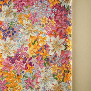 May include: A pink fabric with a floral pattern featuring white, yellow, and pink flowers. The fabric is covered in a variety of flowers, creating a busy and colorful design.