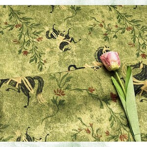 Może przedstawiać: Zbliżenie zielonej tkaniny z powtarzającym się wzorem czarnych koni i element&oacute;w kwiatowych. Tkanina ma teksturowany wygląd. R&oacute;żowy i ż&oacute;łty tulipan z zielonymi liśćmi znajduje się na pierwszym planie.