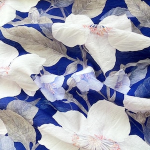 May include: A blue fabric with a white floral pattern. The flowers are large and have a delicate, watercolour-like appearance.