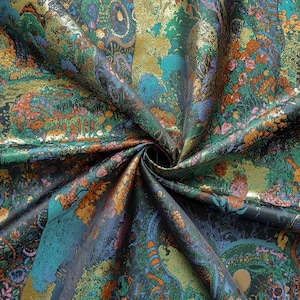 Puede incluir: Primer plano de una tela arremolinada con un dise&ntilde;o floral y paisley detallado. La tela presenta una mezcla de colores, incluyendo verde, turquesa, naranja, dorado y morado. El dise&ntilde;o tiene un brillo met&aacute;lico, d&aacute;ndole una apariencia lujosa.