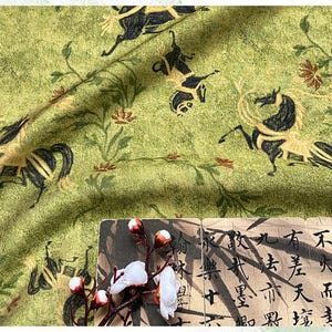 Może przedstawiać: Zielona tkanina z powtarzającym się wzorem czarnych i beżowych koni oraz element&oacute;w kwiatowych. Tkanina ma teksturowany wygląd. Gałązka białych kwiat&oacute;w i kawałek papieru z azjatyckimi znakami znajdują się na pierwszym planie.