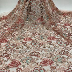 May include: Pink, red, and green sequined lace fabric with a cloud pattern. The fabric has a delicate, sheer texture and is perfect for special occasions.