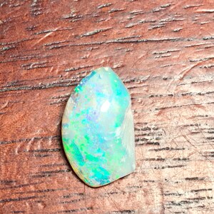 Puede incluir: Una piedra preciosa de ópalo azul claro y verde con destellos iridiscentes.