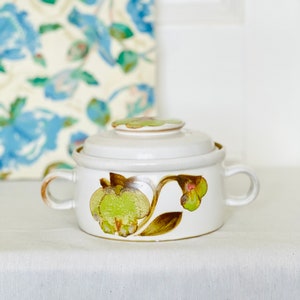 May include: White ceramic casserole dish with a lid. The dish features a floral design with green and brown leaves and flowers.