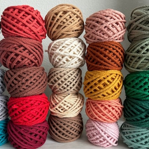 May include: A collection of 18 colorful cotton rope balls, each with a different pattern and color. The balls are arranged in three rows of six, with the colors ranging from red to green.