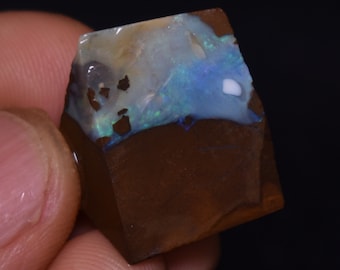 May include: A rough, brown and white opal with a blue and green iridescent sheen. The opal is a raw, unpolished stone.