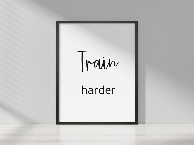 May include: A black framed motivational poster with white background and the text "Train harder" in black cursive font.