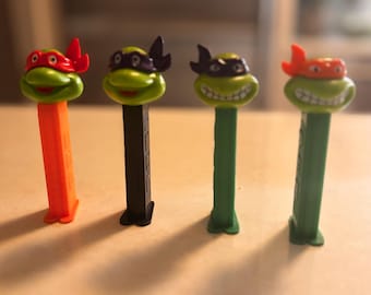 Tortuga ninja Pez naranja, roja y morada sobre tallo verde, negro y naranja