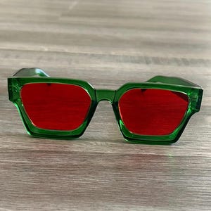 May include: Green square-shaped sunglasses with red lenses.