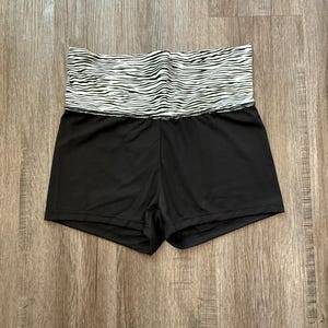 May include: Black athletic shorts with a white and black zebra print waistband.