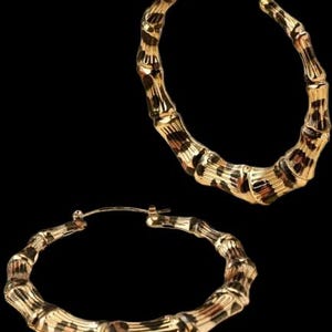 May include: A pair of gold hoop earrings with a bamboo-like design and a leopard print pattern.