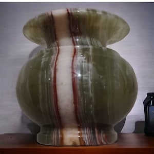 May include: A green, white, and red striped marble vase with a wide mouth and a round body.