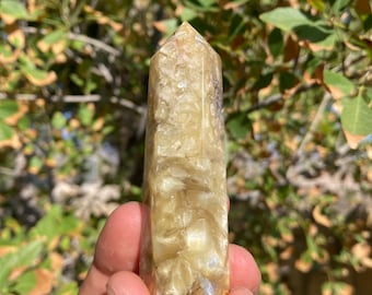 May include: A yellow and white crystal point with a smooth, polished finish. The crystal is about 3 inches long and has a pointed tip.