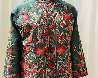 May include: A green embroidered jacket with floral patterns in red, orange, and white. The jacket has a mandarin collar and a button closure.