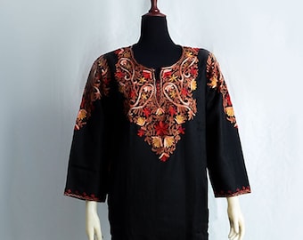 May include: A black long-sleeved tunic with intricate embroidery in shades of red, orange, and gold. The embroidery features a floral design around the neckline.