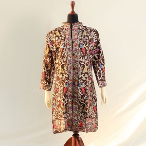 May include: A long brown embroidered tunic with a floral and bird design. The tunic has a mandarin collar and a button-up front.
