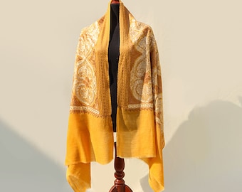 May include: A yellow shawl with a white paisley pattern. The shawl is draped over a wooden mannequin.