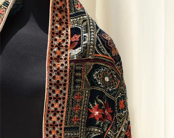 May include: A black velvet shawl with intricate gold and red embroidery. The shawl has a geometric pattern and a decorative border.