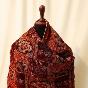 May include: A maroon velvet shawl with intricate gold and green embroidery in a patchwork design.