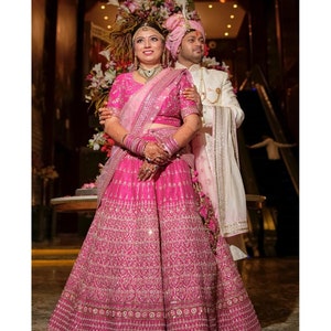 Bridal megenta pink hand embroidered Indian wedding lehenga with floral jal embellished blouse paired with light pink and dark pink dupatta.