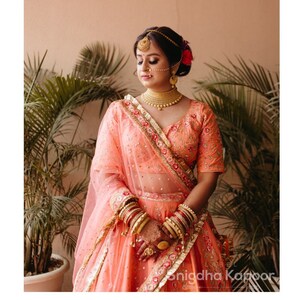Bridal blush peach hand embroidered Indian wedding lehenga with floral jal embellished blouse paired with peach dupatta and ombré veil