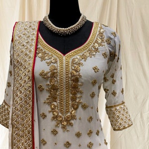 Off white embroidered kurta with heavy embroidered sharara pants and embellished dupatta with contrast pink piping