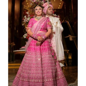 Bridal megenta pink hand embroidered Indian wedding lehenga with floral jal embellished blouse paired with light pink and dark pink dupatta.
