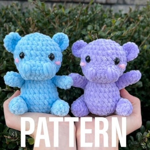Puede incluir: Un patrón de crochet para hacer dos peluches de hipopótamo. Uno es azul claro y el otro es lavanda. El patrón está escrito sobre un fondo blanco con la palabra "PATTERN" en letras blancas grandes y en negrita.