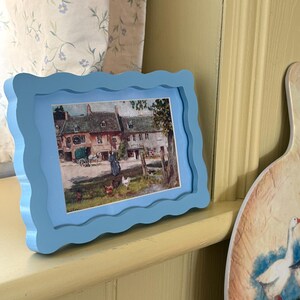 Blauer gewellter Fotorahmen mit Hütte, Dorfpostkarte. Wandkunst. Bilderrahmen, Wanddeko,