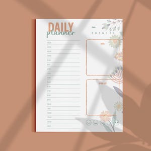 May include: A white daily planner with the words "DAILY planner" in orange and teal. The planner has sections for time slots, notes, and a to-do list, with floral accents and smiley face icons.