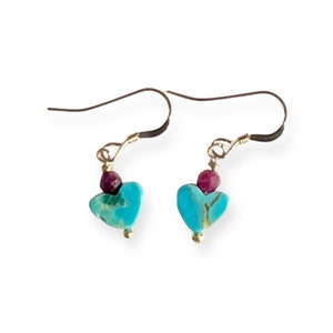 May include: A pair of turquoise heart-shaped earrings with a small ruby bead at the top of each heart.