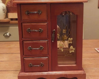 Boîte à bijoux en bois Mele avec miroir et suspension derrière une porte fleurie. Quatre tiroirs avec intérieur rose. Usure vintage normale.