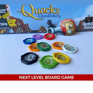 以下が含まれることがあります： 異なる番号と画像が描かれたカラフルなゲームトークンのセット。トークンはプラスチック製で、光沢のある仕上げになっています。ゲームの名前は「The Quacks of Quedlinburg」です。