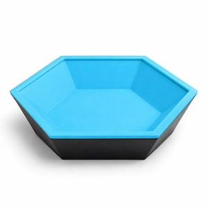 Puede incluir: Un cuenco hexagonal con exterior negro e interior azul brillante. El cuenco tiene un diseño geométrico moderno y probablemente está hecho de plástico o material similar. El cuenco está vacío y sobre un fondo blanco.