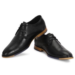 Peut inclure: Une paire de chaussures en cuir noir à lacets avec un motif texturé. Les chaussures ont une semelle marron et une bordure bleue.