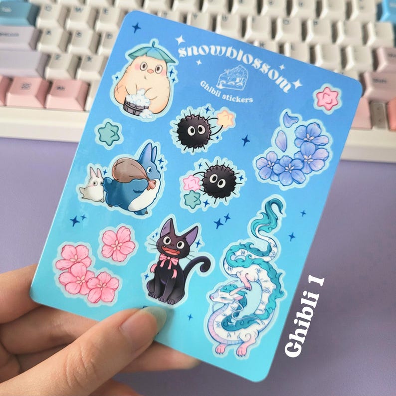May include: A sheet of blue stickers featuring characters from Studio Ghibli films. The stickers include Totoro, No Face, Jiji, and the dragon from Spirited Away. The sheet is titled "snowblossom Ghibli stickers" and "Ghibli 1" in the bottom right corner.