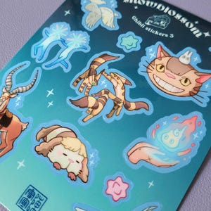 May include: A sheet of stickers featuring characters from Studio Ghibli films. The stickers are on a blue background with white stars. The stickers include Totoro, the Catbus, No Face, and other characters. The text "Studio Ghibli Stickers 5" is printed on the sheet.