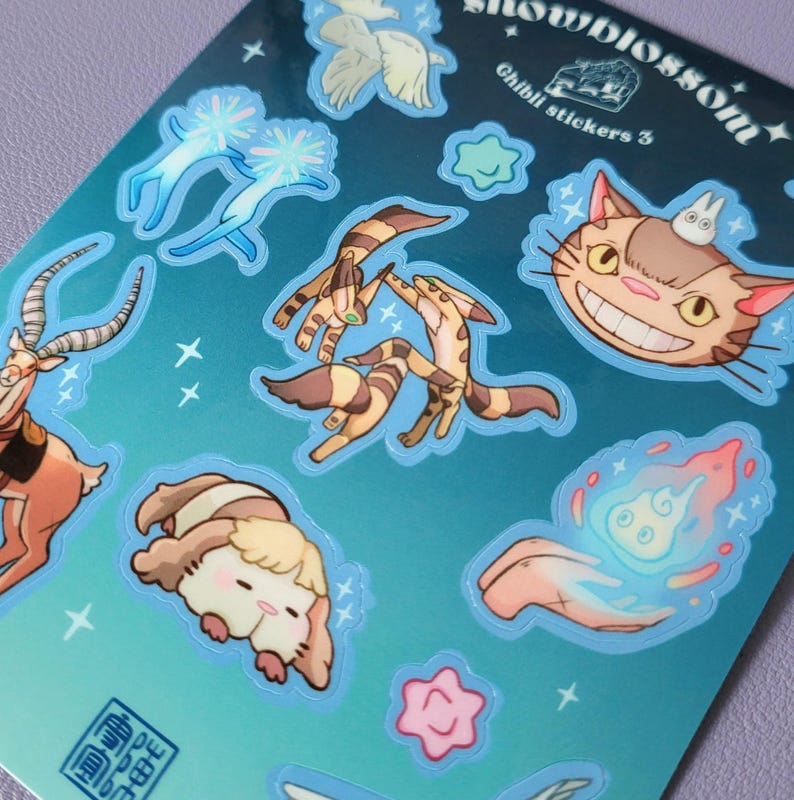 May include: A sheet of stickers featuring characters from Studio Ghibli films. The stickers are on a blue background with white stars. The stickers include Totoro, the Catbus, No Face, and other characters. The text "Studio Ghibli Stickers 5" is printed on the sheet.