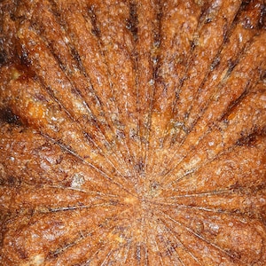 May include: A golden brown banana bread loaf with a starburst pattern on top, baked and cooling on a wire rack.