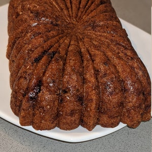 May include: A brown, star-shaped cake with a shiny glaze. The cake is on a white plate.