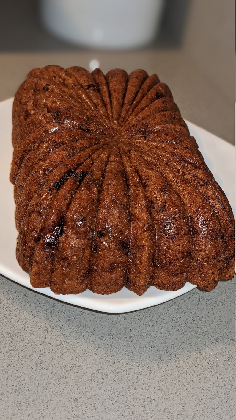 May include: A brown, star-shaped cake with a shiny glaze. The cake is on a white plate.