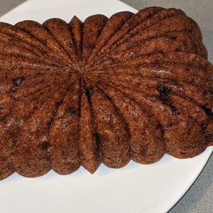 May include: A brown loaf cake with a starburst pattern baked in a fluted loaf pan.